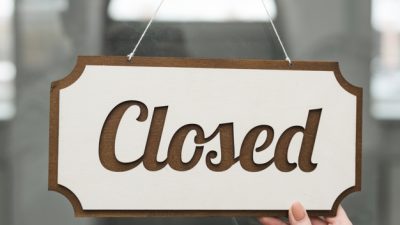 primer-plano-mano-mujer-sosteniendo-etiqueta-cerrada-puerta-vidrio_23-2148028045